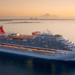 Carnival cruise ship sailing at sunset, highlighting strong travel demand and renewed investor confidence