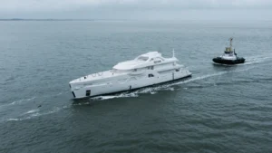 The hull of an Amels 60 superyacht under tow during construction at sea, showing the vessel’s exterior profile