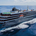 Atlas Ocean Voyages expedition cruise ship sailing through open ocean, showcasing its helipad, exploration-focused design, and premium small-ship layout.