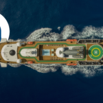 Aerial top-down view of an Atlas Ocean Voyages expedition cruise ship sailing through deep blue ocean waters, showing the helipad and open deck layout.