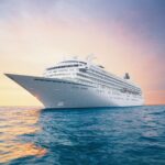 Crystal Symphony cruise ship sailing at sunset with a calm ocean and warm sky in the background