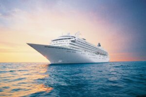 Crystal Symphony cruise ship sailing at sunset with a calm ocean and warm sky in the background