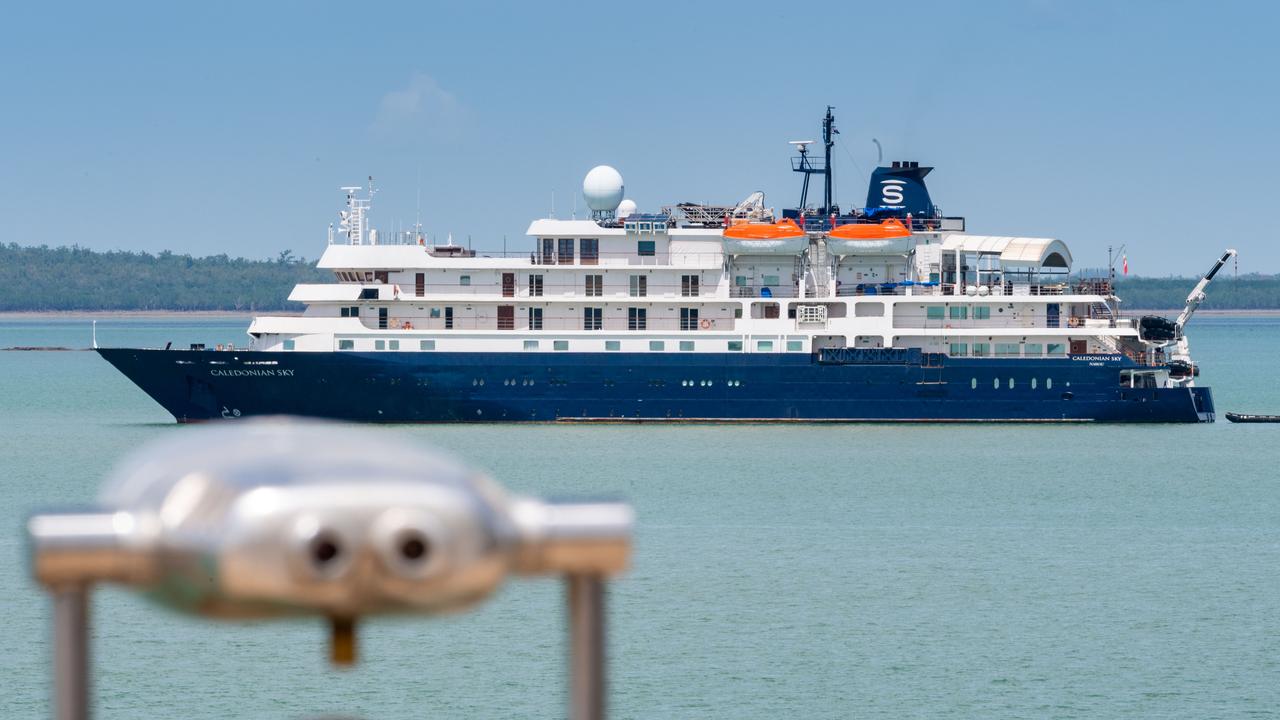 The expedition cruise ship Caledonian Sky anchored in calm waters, showing its blue hull and white superstructure