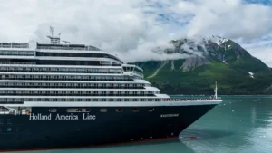 Holland America Line cruise ship sailing through Alaska fjords with mountains in the background