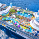 Aerial view of Royal Caribbean’s Icon of the Seas featuring a full waterpark, multiple pools, and colorful deck attractions at sea.