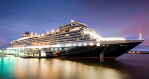 Cunard’s Queen Elizabeth cruise ship docked at night, illuminated along the waterfront during her 15th year of service
