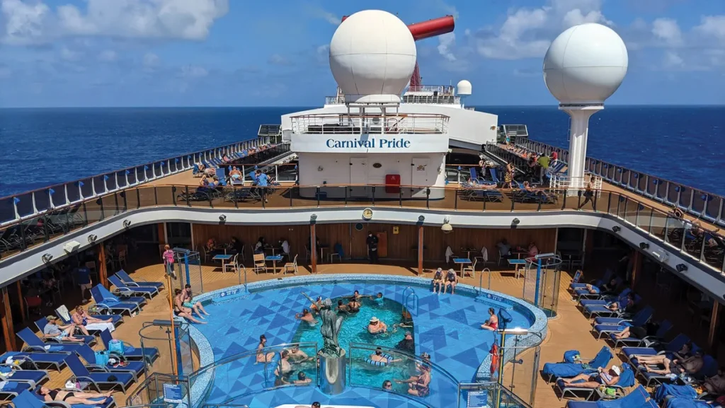 Passengers relax around the main pool deck aboard Carnival Pride during a Carnival Journeys cruise sailing from Baltimore.