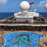 Passengers relax around the main pool deck aboard Carnival Pride during a Carnival Journeys cruise sailing from Baltimore.