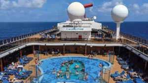 Passengers relax around the main pool deck aboard Carnival Pride during a Carnival Journeys cruise sailing from Baltimore.