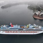 Aerial view of Carnival Splendor cruising through Sydney Harbour with the Sydney Opera House in the background