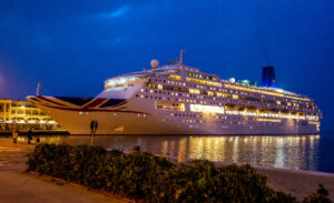 MV Piano Land cruise ship illuminated at night while docked in Hong Kong harbor ahead of its regional return to Asia