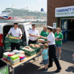 P&O Cruises officers distribute surplus food outside a Southampton community food share, helping families while reducing shipboard food waste.