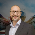 Roland Schwandt, newly appointed CEO of Schottel, pictured at a shipyard with a vessel under construction in the background.