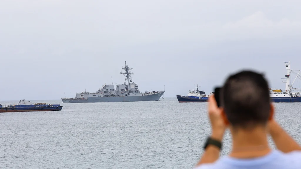 A US Navy warship operates near Venezuelan waters as regional tensions lead to flight cancellations and travel disruptions affecting Caribbean cruise passengers.