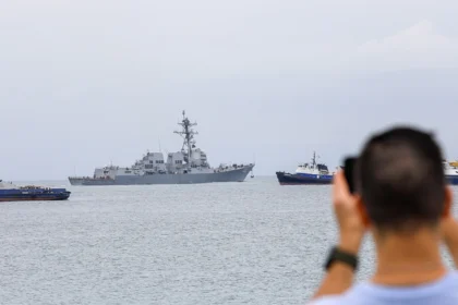 A US Navy warship operates near Venezuelan waters as regional tensions lead to flight cancellations and travel disruptions affecting Caribbean cruise passengers.
