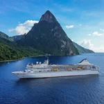 Villa Vie Odyssey residential cruise ship sailing near Saint Lucia with the Pitons rising in the background under clear blue skies.