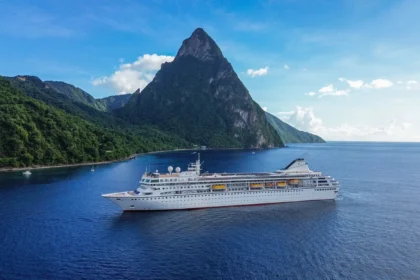 Villa Vie Odyssey residential cruise ship sailing near Saint Lucia with the Pitons rising in the background under clear blue skies.