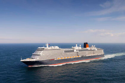 Cunard’s Queen Anne cruise ship sailing at sea during a 2026 voyage, showcasing the luxury ocean liner’s exterior profile and signature black-and-red funnel design.