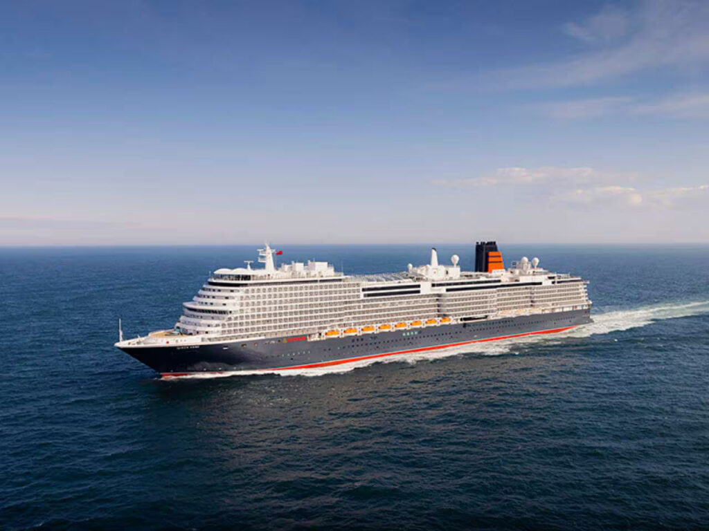 Cunard’s Queen Anne cruise ship sailing at sea during a 2026 voyage, showcasing the luxury ocean liner’s exterior profile and signature black-and-red funnel design.